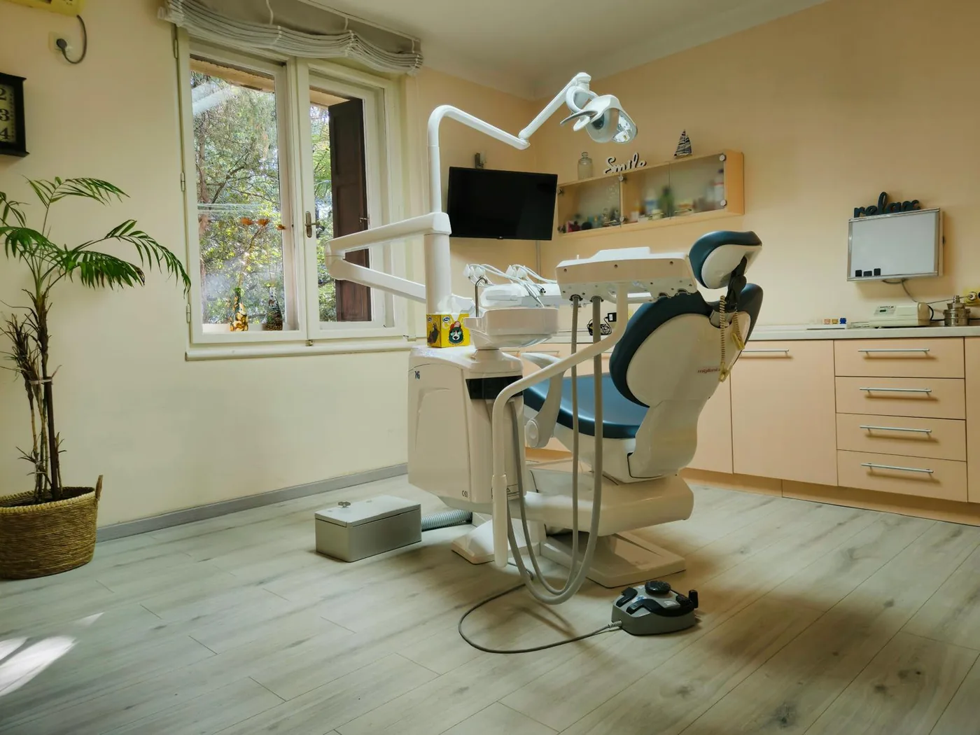 Ordinacija dentalne medicine s dentalnim stolcem uz prozor s pogledom na zelenilo